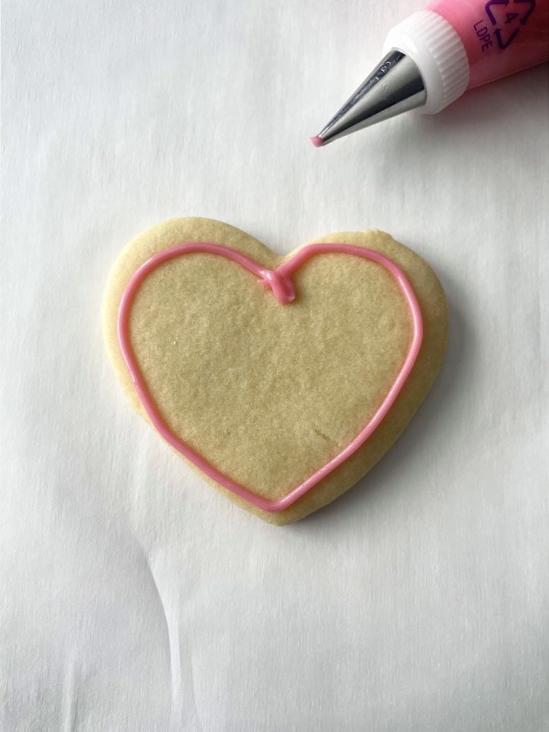 heart shaped cookie with pink icing outline